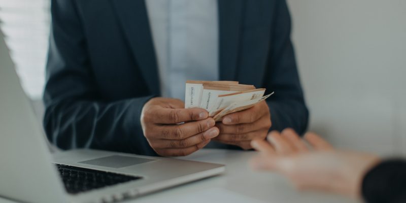 Businessman giving money to his partner while making contract - bribery and corruption concepts