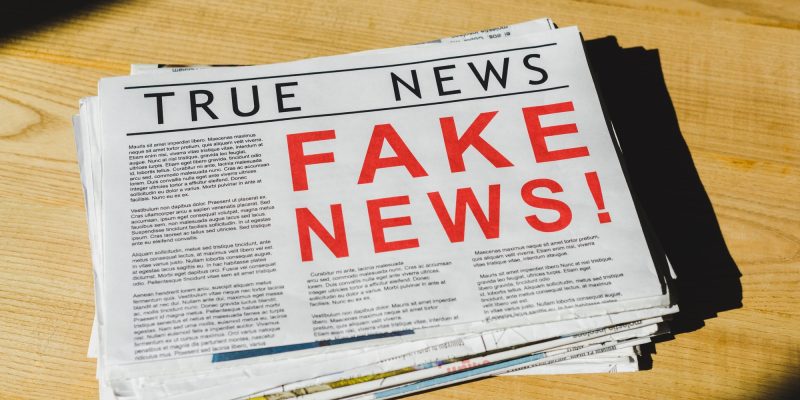 pile of newspapers with fake and true news on wooden table