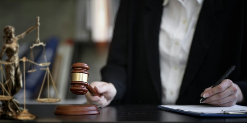 Woman judge hand holding gavel to bang on sounding block in the court room.