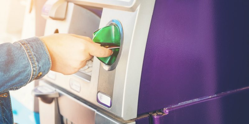 Women nand inserting ATM credit card into bank machine